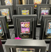 Collection of trading cards in display cases on a gray surface